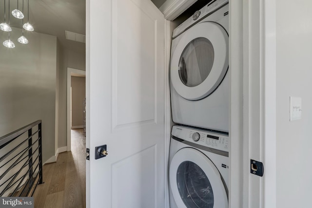 clothes washing area featuring hardwood / wood-style flooring and stacked washer / dryer