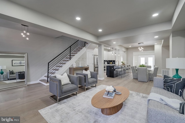 living room with french doors, light hardwood / wood-style floors, and sink