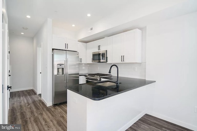 kitchen featuring kitchen peninsula, dark hardwood / wood-style flooring, white cabinets, and stainless steel appliances