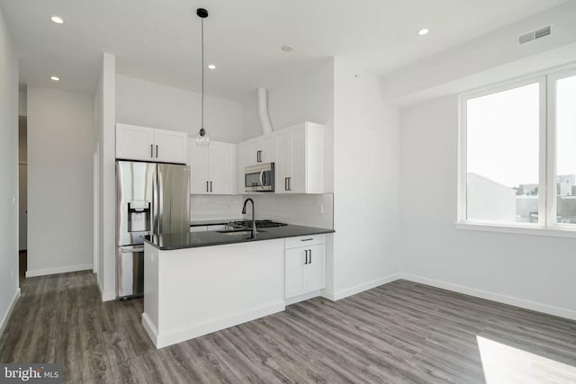 kitchen featuring dark wood-type flooring, sink, hanging light fixtures, appliances with stainless steel finishes, and white cabinetry