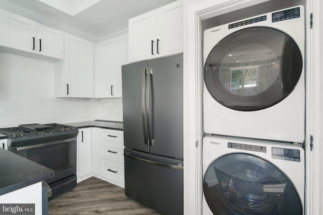 kitchen with white cabinetry, dark hardwood / wood-style floors, stainless steel fridge, stacked washer and dryer, and black range with gas cooktop