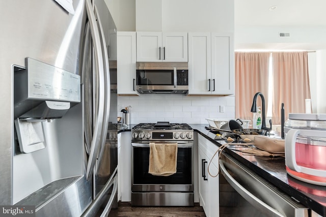 kitchen with white cabinets, decorative backsplash, stainless steel appliances, and dark wood-type flooring