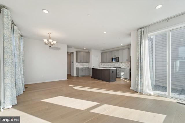 unfurnished living room featuring a chandelier and light hardwood / wood-style flooring