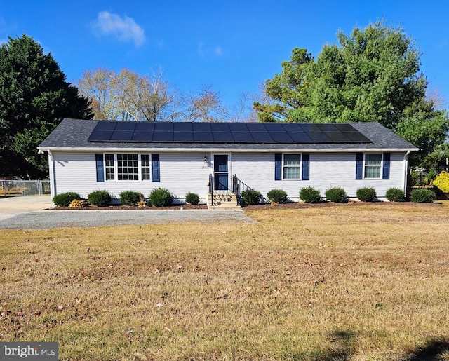 ranch-style house featuring solar panels and a front lawn