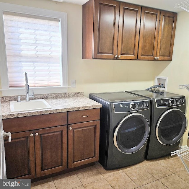 clothes washing area with washing machine and dryer, sink, light tile patterned floors, and cabinets