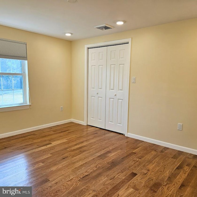 unfurnished bedroom with wood-type flooring and a closet