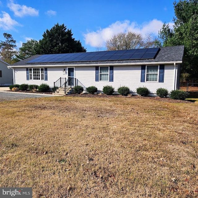 single story home featuring solar panels and a front lawn