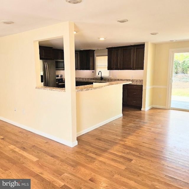 kitchen featuring dark brown cabinetry, light hardwood / wood-style flooring, and appliances with stainless steel finishes