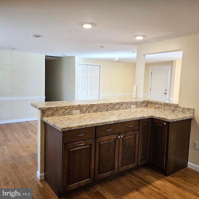 kitchen with dark brown cabinetry, kitchen peninsula, and dark hardwood / wood-style floors