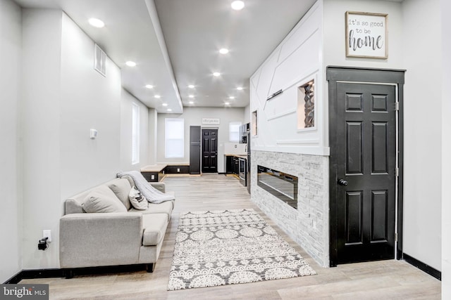 living room featuring a stone fireplace and light wood-type flooring