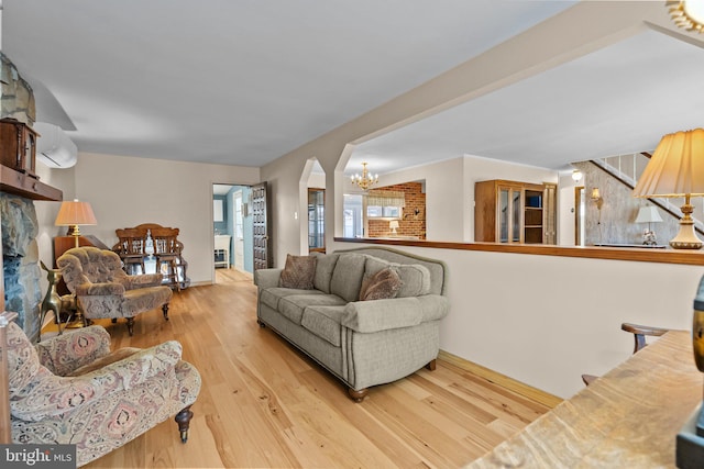 living room featuring light wood-type flooring, a wall mounted AC, and a chandelier