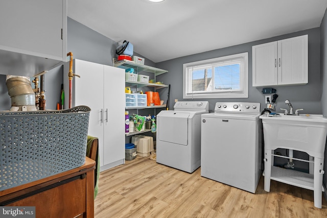 clothes washing area featuring cabinets, light hardwood / wood-style floors, and independent washer and dryer