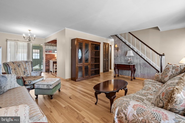 living room with a fireplace, hardwood / wood-style floors, an inviting chandelier, and ornamental molding