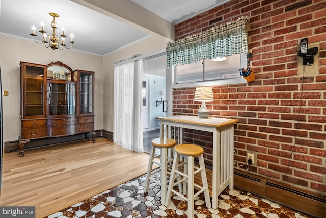 dining room with an inviting chandelier, light hardwood / wood-style flooring, brick wall, a baseboard heating unit, and crown molding