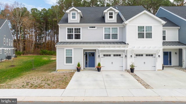 view of property with a front yard, driveway, a standing seam roof, an attached garage, and metal roof