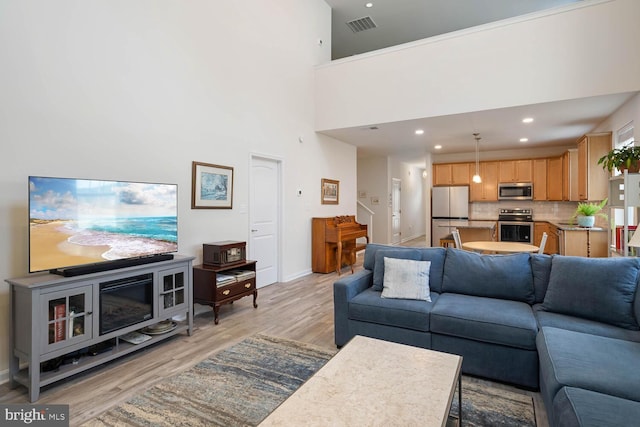 living room with light hardwood / wood-style floors and a high ceiling