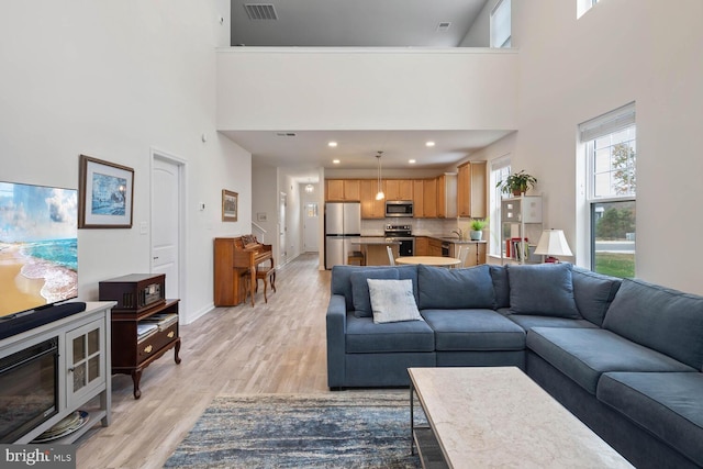 living room with light hardwood / wood-style floors and a high ceiling