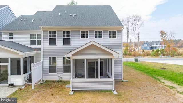 back of property featuring a sunroom and a lawn