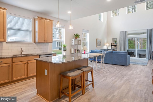 kitchen featuring sink, a center island, a kitchen breakfast bar, dark stone countertops, and light wood-type flooring