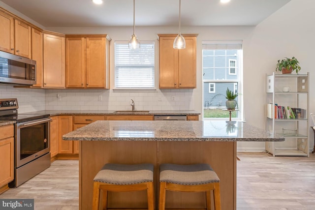 kitchen with appliances with stainless steel finishes, light hardwood / wood-style flooring, a healthy amount of sunlight, and sink