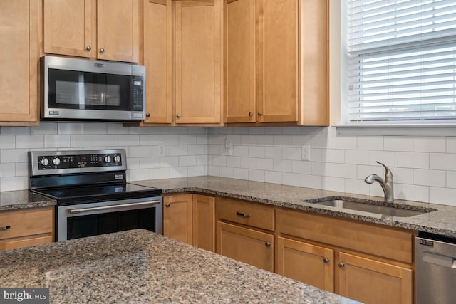 kitchen featuring light stone countertops, stainless steel appliances, tasteful backsplash, and sink