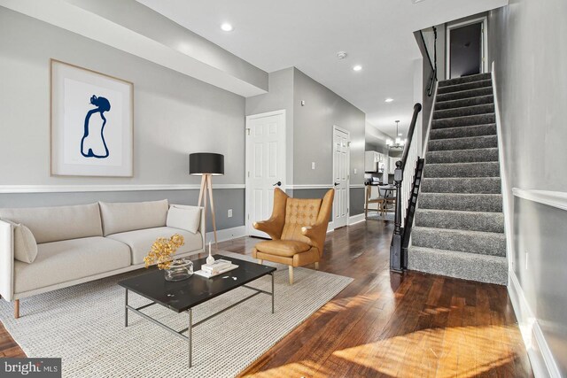 living room with dark hardwood / wood-style flooring and an inviting chandelier