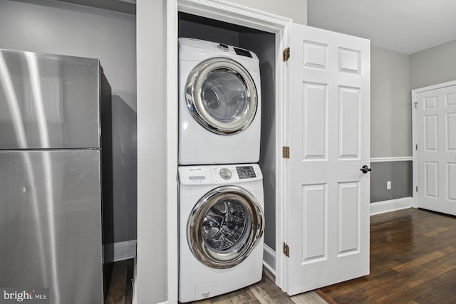 laundry room featuring stacked washing maching and dryer and dark hardwood / wood-style floors