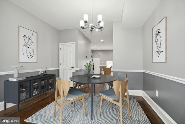 dining area featuring dark wood-type flooring and an inviting chandelier