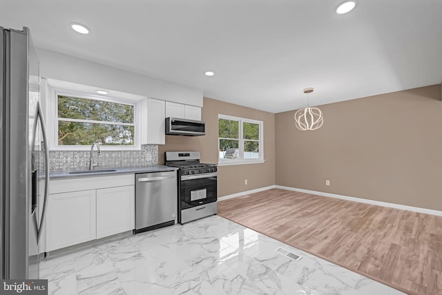 kitchen featuring decorative backsplash, stainless steel appliances, sink, light hardwood / wood-style flooring, and white cabinets