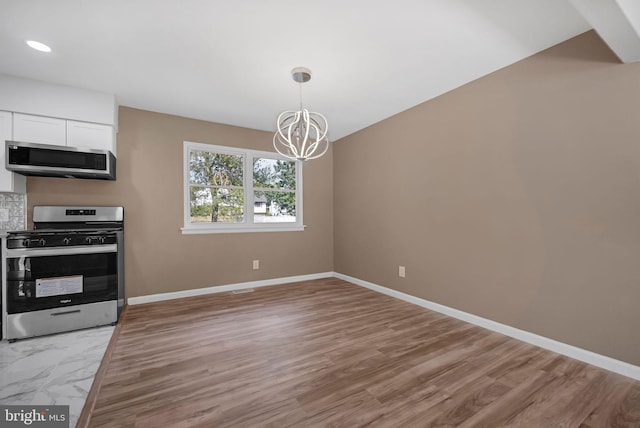 kitchen featuring hardwood / wood-style floors, white cabinets, appliances with stainless steel finishes, decorative light fixtures, and a chandelier