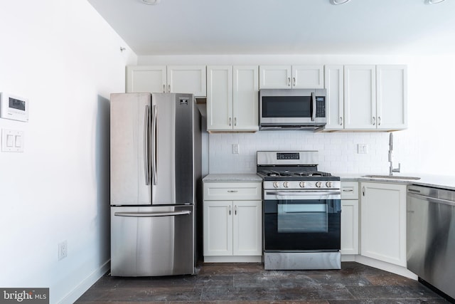 kitchen featuring tasteful backsplash, sink, white cabinets, and appliances with stainless steel finishes