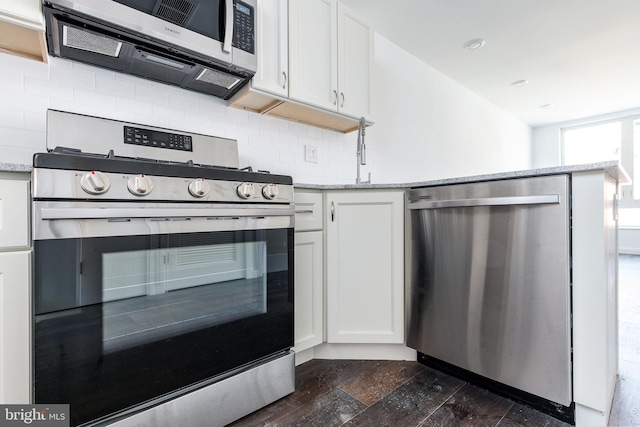 kitchen with appliances with stainless steel finishes, dark hardwood / wood-style floors, white cabinetry, and light stone counters