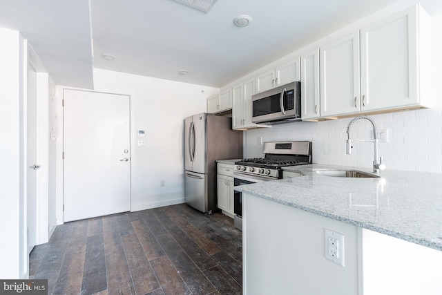 kitchen with sink, dark hardwood / wood-style flooring, light stone counters, white cabinetry, and stainless steel appliances