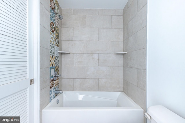 bathroom featuring tiled shower / bath combo and toilet