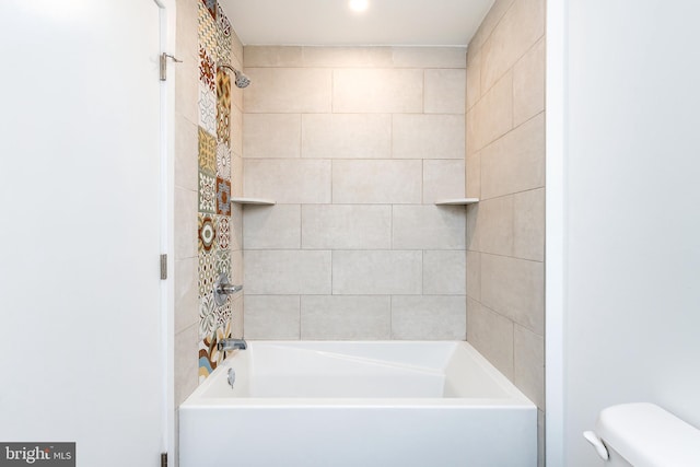 bathroom featuring toilet and tiled shower / bath