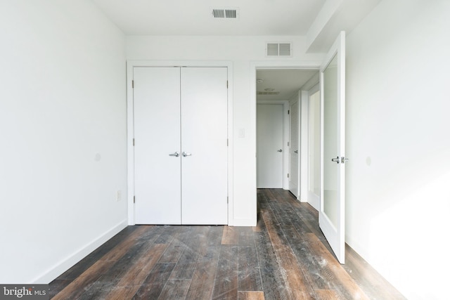 unfurnished bedroom with a closet and dark hardwood / wood-style flooring