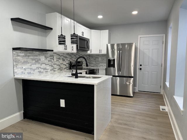 kitchen featuring kitchen peninsula, appliances with stainless steel finishes, light wood-type flooring, sink, and white cabinetry