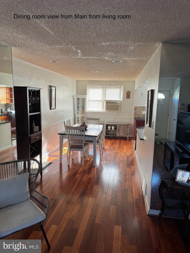 dining area with cooling unit, a textured ceiling, and hardwood / wood-style flooring