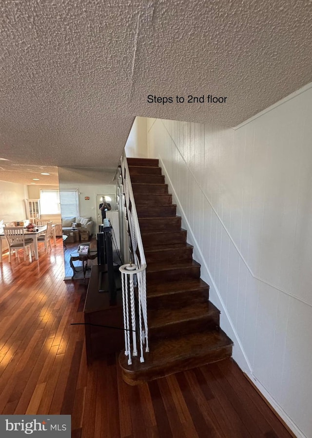 stairway featuring wood-type flooring and a textured ceiling