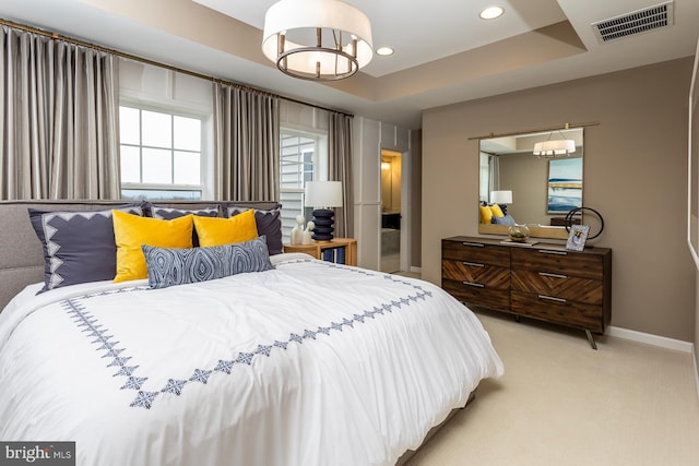 carpeted bedroom featuring a raised ceiling and a notable chandelier