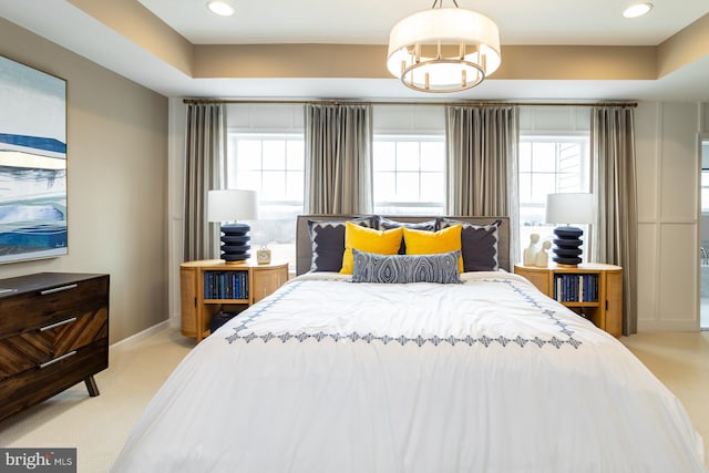 carpeted bedroom with a notable chandelier and a raised ceiling