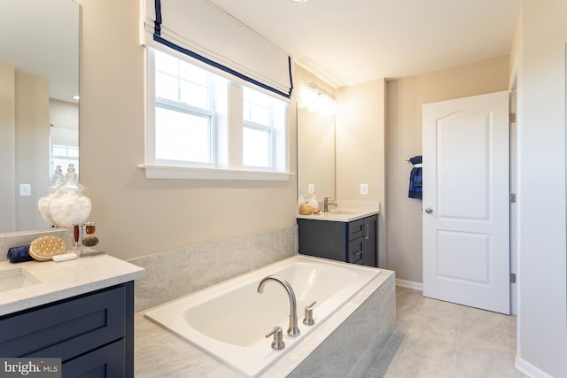 bathroom featuring tile patterned flooring, vanity, and tiled bath