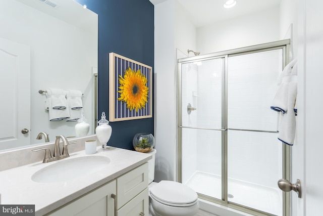 bathroom with a shower with door, vanity, and toilet