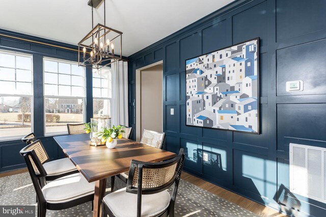 dining room with hardwood / wood-style flooring, an inviting chandelier, and ornamental molding