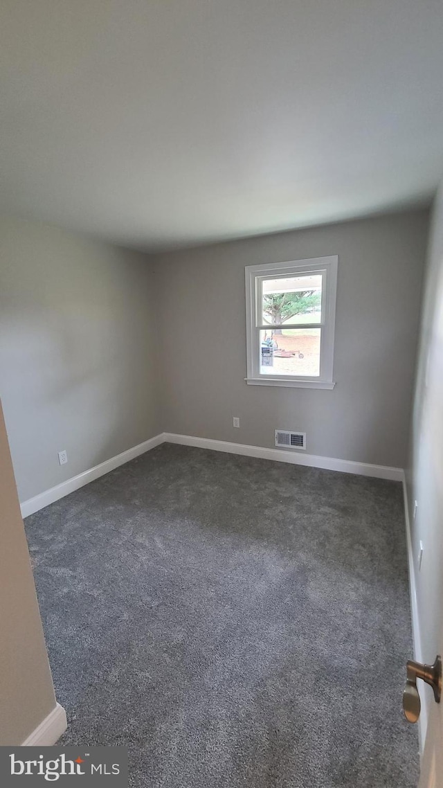 unfurnished room with dark colored carpet