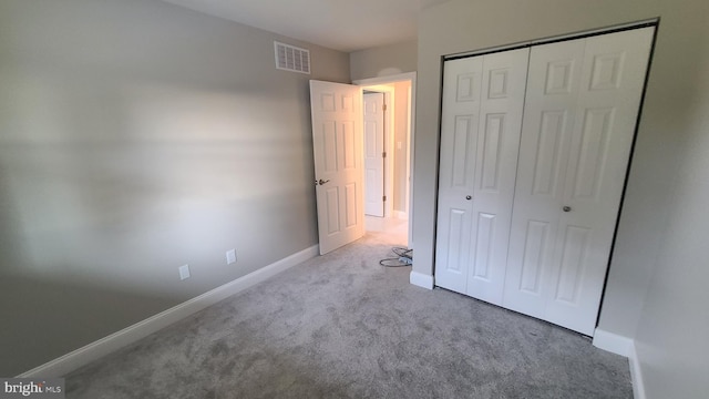 unfurnished bedroom featuring light carpet and a closet