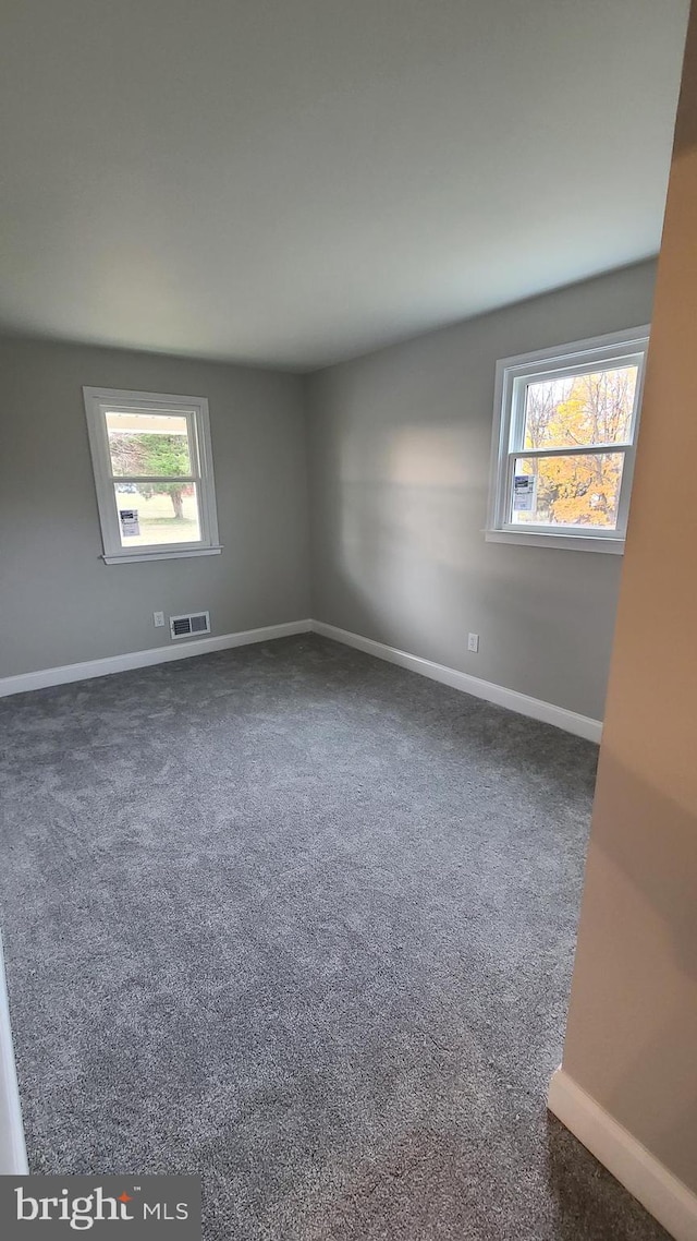 unfurnished room featuring dark colored carpet