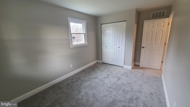 unfurnished bedroom with light colored carpet and a closet