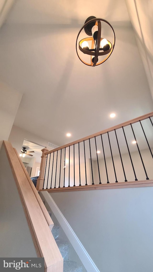 stairs featuring ceiling fan with notable chandelier