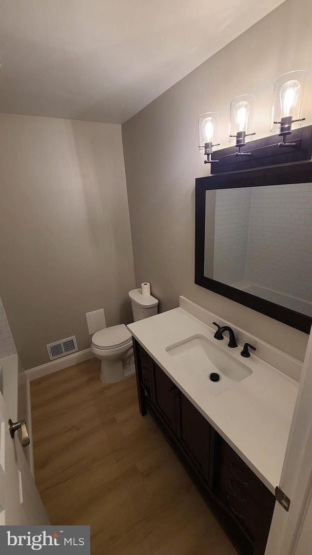 bathroom with hardwood / wood-style flooring, vanity, and toilet